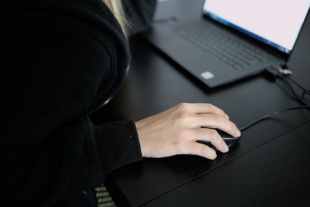Hands of Caucasian woman in foreground working on computer on deskの写真素材
