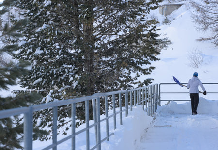 Woman cleans road from snowの写真素材