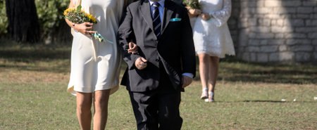 Two half-body people walk towards the civil wedding with flowers in their hands in a large meadowの写真素材