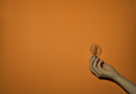 Presentation of old halogen bulb on the right and negative space on the left against an orange...
