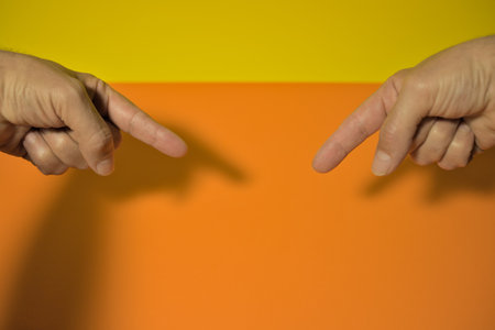 Two hands pointing with fingers in center image on orange backgroundの写真素材