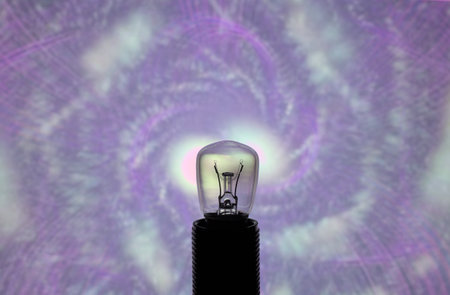 An image of a light bulb on a purple abstract background.の写真素材
