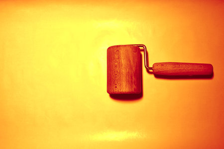 Wooden paint roller on a yellow background. Selective focus.の写真素材