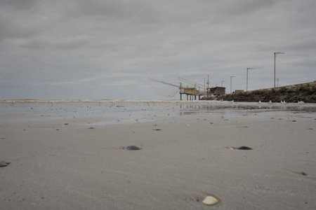 View of the beach at low tide with fishing boats in the backgroundの写真素材