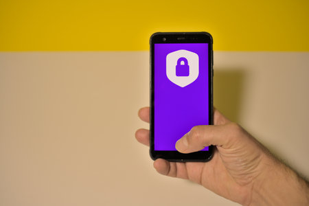 Hand holding a smartphone displaying logo of Opened Padlock on the screen. Opened Padlock is used to secure online transactions.の写真素材