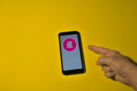 index finger pointing to the pound icon on screen smartphone icon red dollar icon in the shape of a circle on a yellow backgroundの写真素材