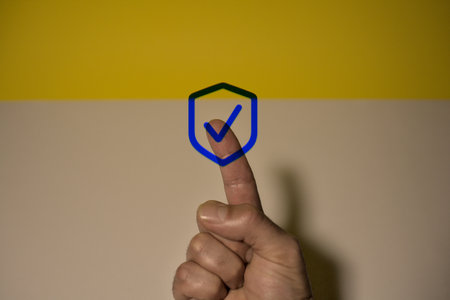 Hand with a check mark on the background of a yellow wall.の写真素材
