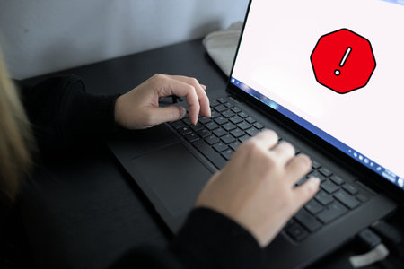 Woman working on laptop with exclamation mark icon on the screen.