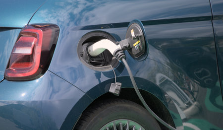 Charging an electric car with an electric plug in a blue carの写真素材