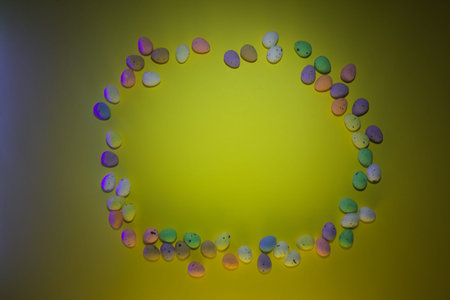 Round frame made of multicolored marshmallows on a yellow backgroundの写真素材