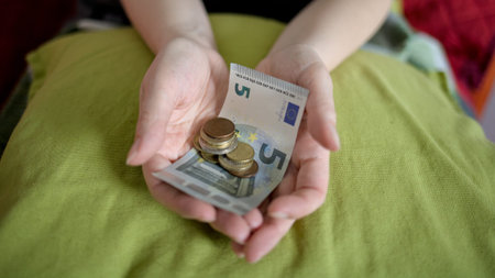 Female hands holding euro banknotes and coins, close-up.