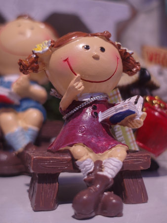 Ceramic figurine of a girl sitting on a wooden benchの写真素材
