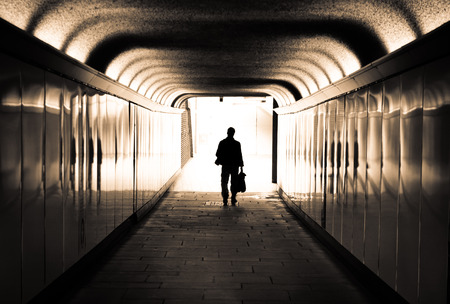 Man walking in a tunnel towards the lightの写真素材