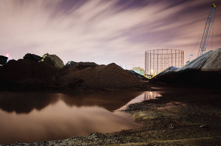 Urban scene in a building site at night. Reflection of artificial hills in a puddle. In the...
