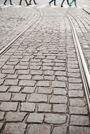 Blurred people zebra crossing on cobblestone pavement. Tramway tracks in foregroundの写真素材