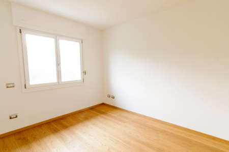 Spacious empty room with white walls, window and parquet floorの写真素材