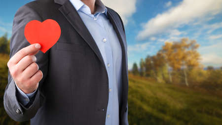 Businessman with heart on natural backgroundの写真素材