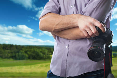 Young man holds modern digital black cameraの写真素材