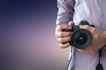 Young man holds modern digital black cameraの写真素材