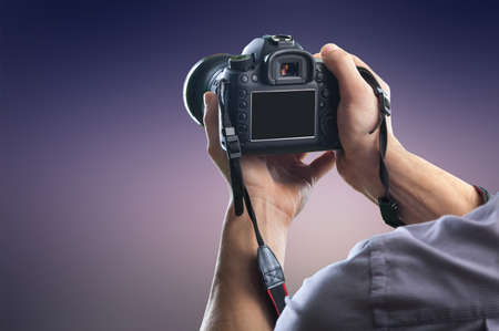 Young man holds modern digital black cameraの写真素材