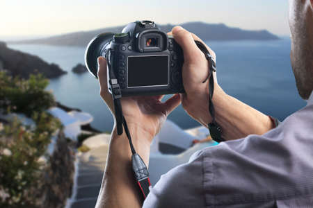 Young man holds modern digital black cameraの写真素材