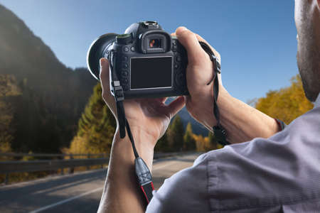 Young man holds modern digital black cameraの写真素材