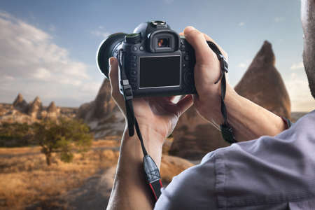 Young man holds modern digital black cameraの写真素材
