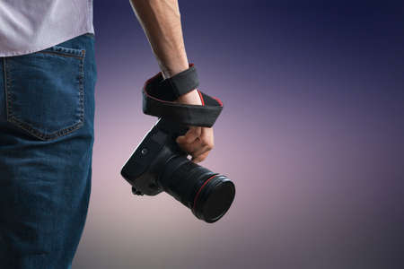 Young man holds black modern digital cameraの写真素材
