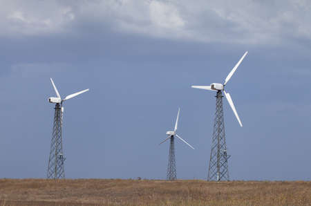 Electricity wind power generators in the field against the skyの写真素材