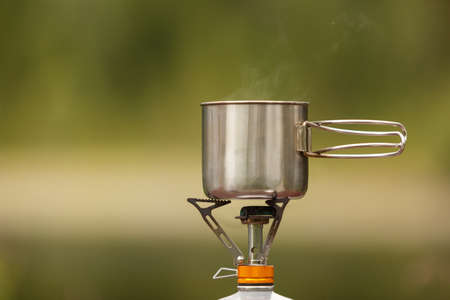 The camping iron mug with a gas burner on natural bokeh backgroundの写真素材
