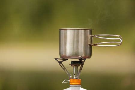 The camping iron mug with a gas burner on natural bokeh backgroundの写真素材