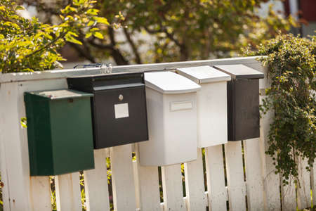 White and green mailboxes on a wooden white fence on natural backgroundの写真素材