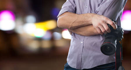 Young man holds black modern digital camera on natural backgroundの写真素材