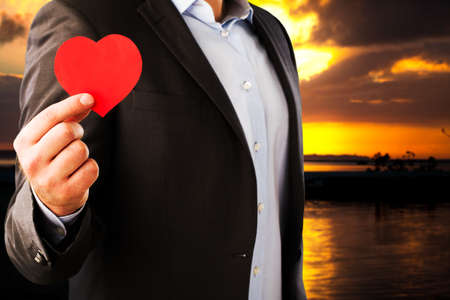 Businessman in a classic suit with an red heart on a dark night backgroundの写真素材