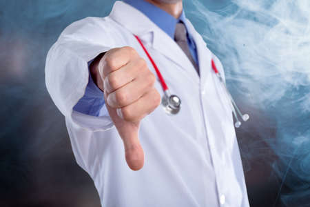 Young doctor with a stethoscope shows bad sign with his handsの写真素材