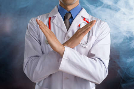 Young doctor with a stethoscope shows stop sign with his handsの写真素材