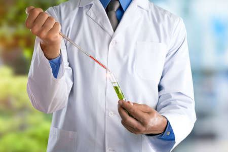 Young doctor with a stethoscope shows tube with blood or plantの写真素材