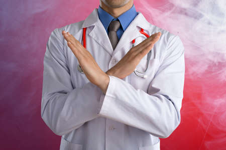 Young doctor shows stop sign with hands on abstract gradient backgroundの写真素材