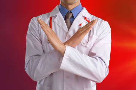 Young doctor shows stop sign with hands on abstract gradient backgroundの写真素材
