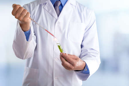 Young doctor with a stethoscope shows tube with blood or plant on pastel gradien backgroundの写真素材