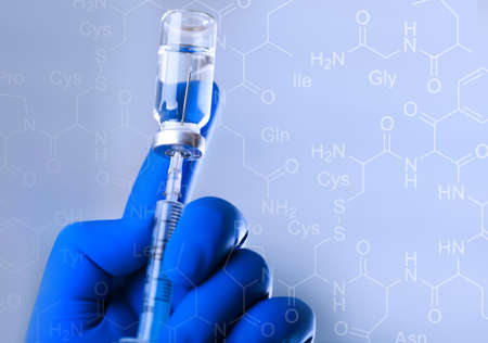 A medical hand in a glove holds an ampoule with a vaccine and a syringe with illustrationの写真素材
