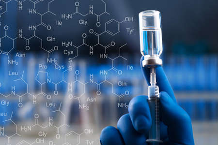A medical hand in a glove holds an ampoule with a vaccine and a syringe with illustrationの写真素材