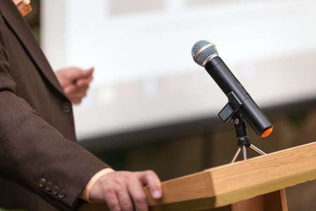 A man stands behind a stand with a microphone and holds a conferenceの写真素材