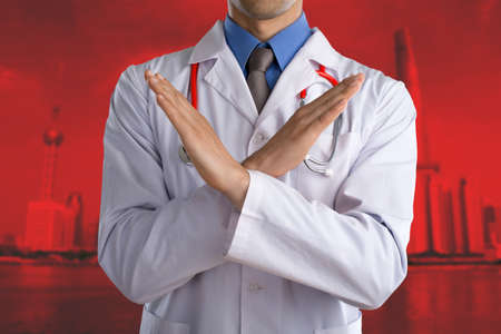 Young doctor with a stethoscope shows stop. Concept sign with his handsの写真素材