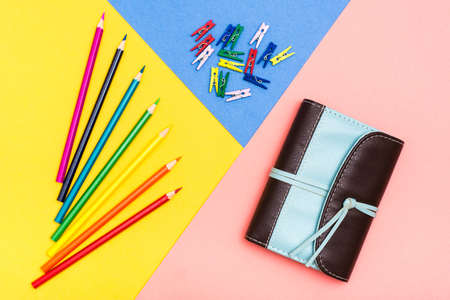 Colored pencils, colored clothespins and organizer on a tricolor background. Rainbow palette