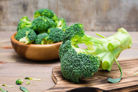 Ready to eat fresh uncooked broccoli on a cutting board and divided into inflorescences in a wooden...