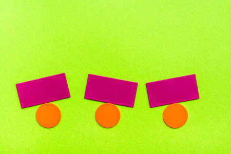 Flat colored shapes - circles and rectangles - simulate balancing on green cardboard. The concept of equilibrium. Copy spaceの写真素材