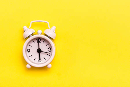 White classic alarm clock on a yellow backgroundの写真素材