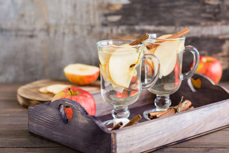 Warm soothing tea made from apples and cinnamon in glasses on a wooden table. Detox concept, antidepressant. Rustic styleの写真素材