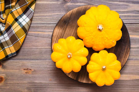 Three fresh bush pumpkin on a cutting board on wooden background. Top viewの写真素材